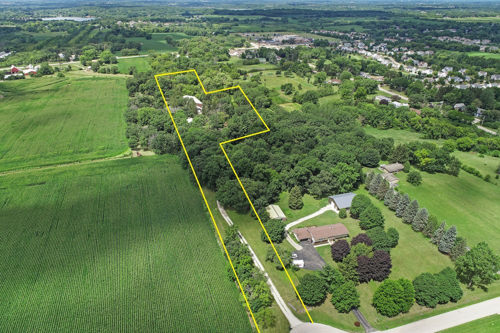 Aerial view of a rural property with a house and outbuildings, outlined in yellow to indicate the parcel boundaries