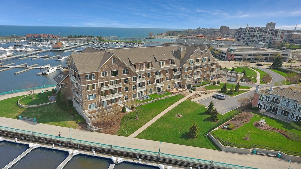 Aerial view of a multi-story residential building with balconies overlooking a marina and lakefront