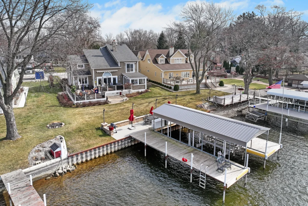 Aerial view of two lakeside houses with private docks and decks on a sunny day