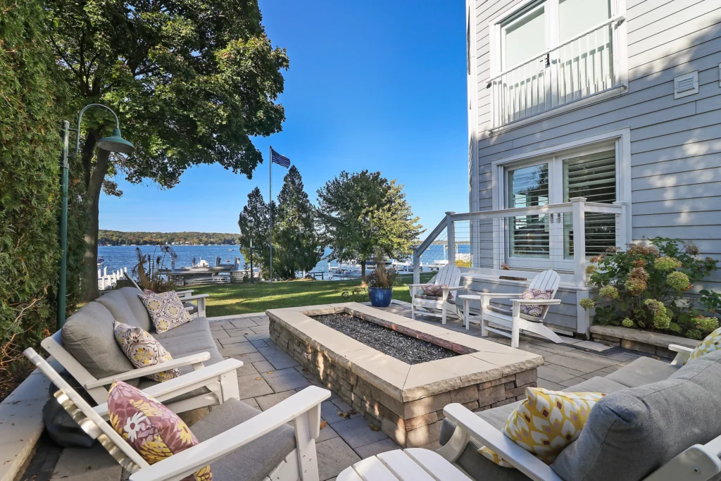 Patio with a stone fire pit and outdoor seating overlooking a lake